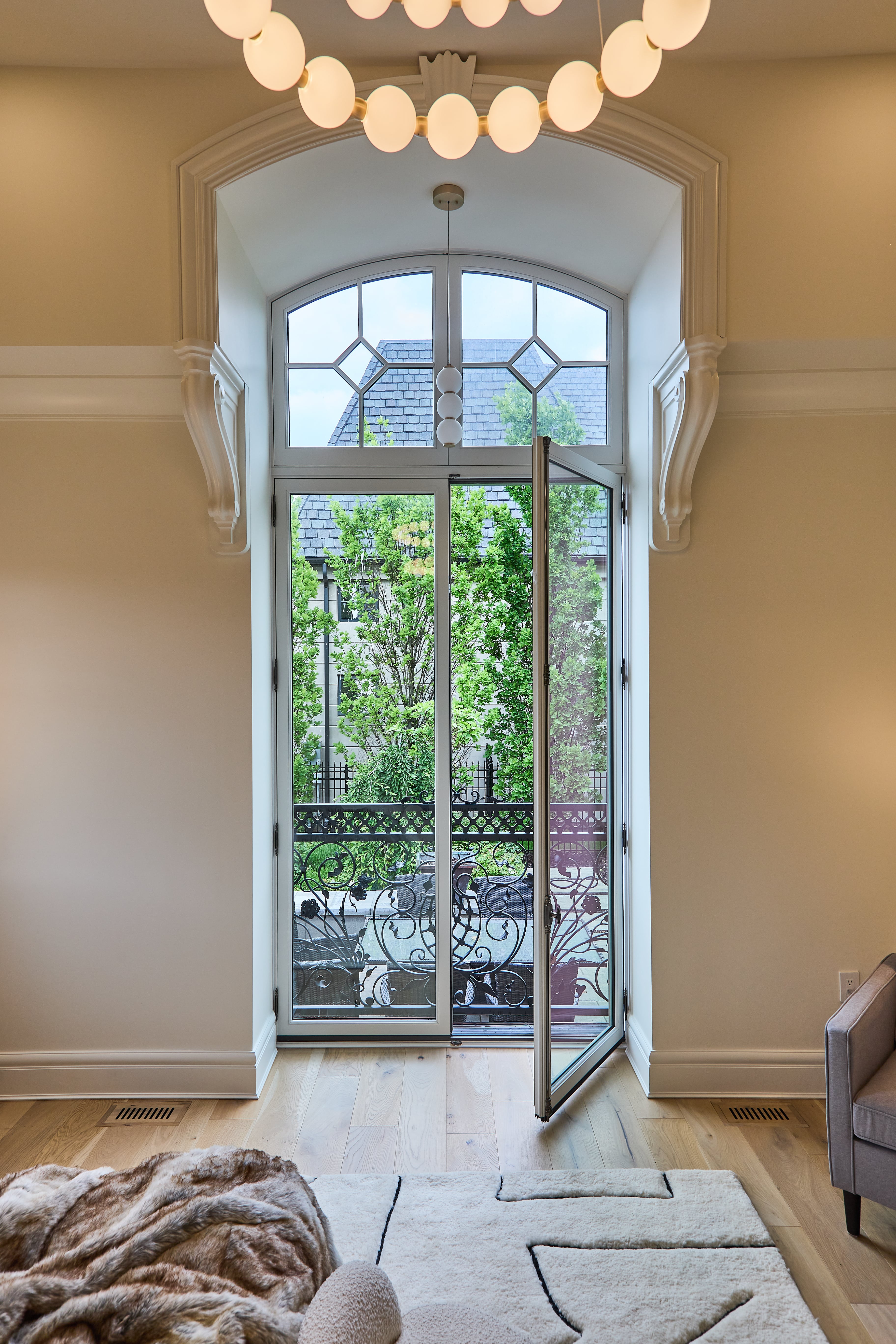Elegant bedroom with intricate molding framing white double doors with diamond detail in transom.