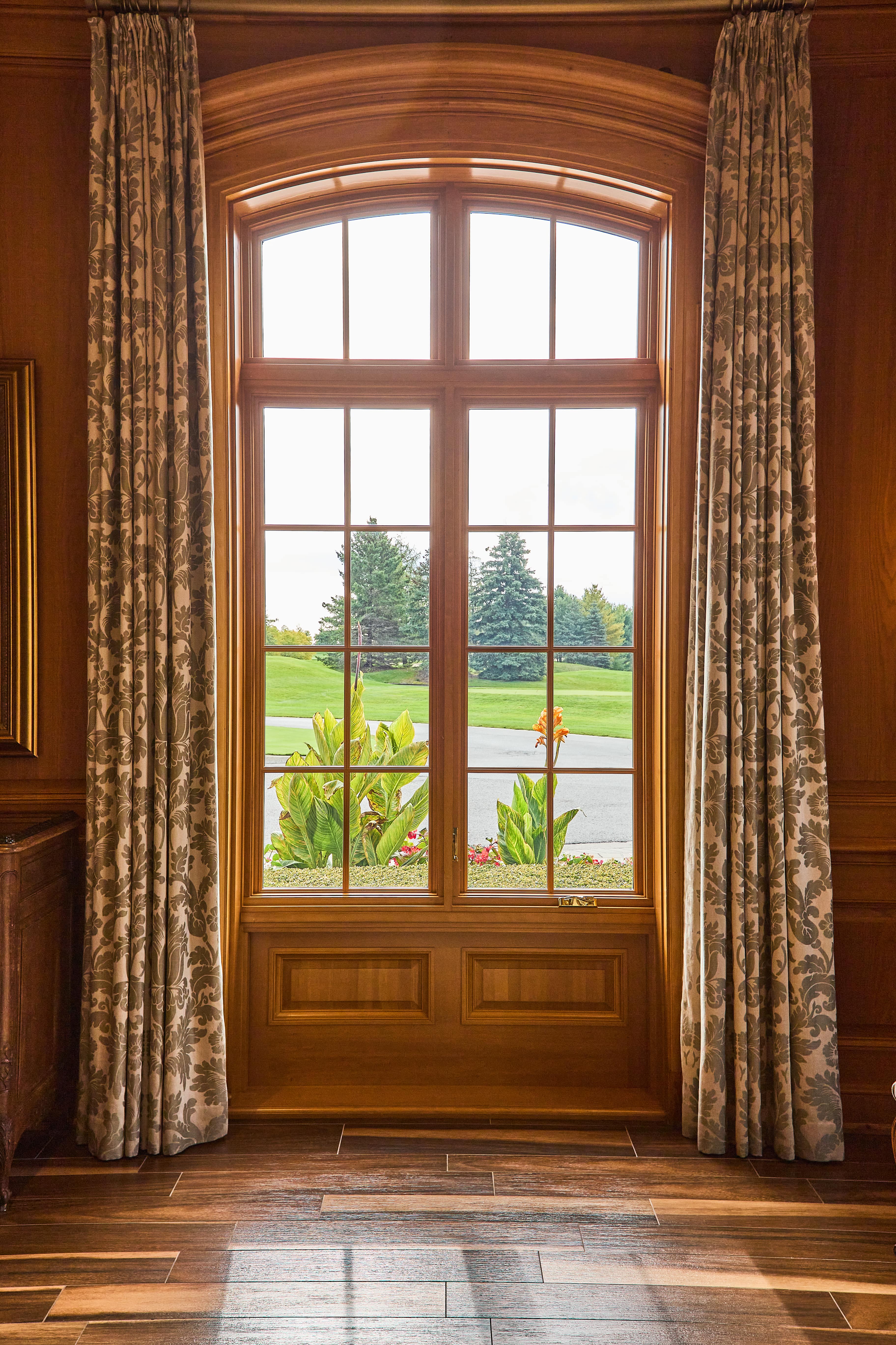 Traditional wooden window with intricate details and long, floral curtains.